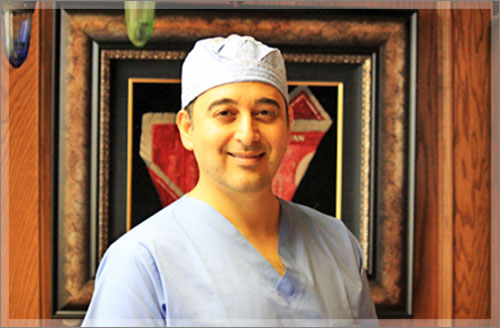 A man in scrubs and a hat standing next to a painting.